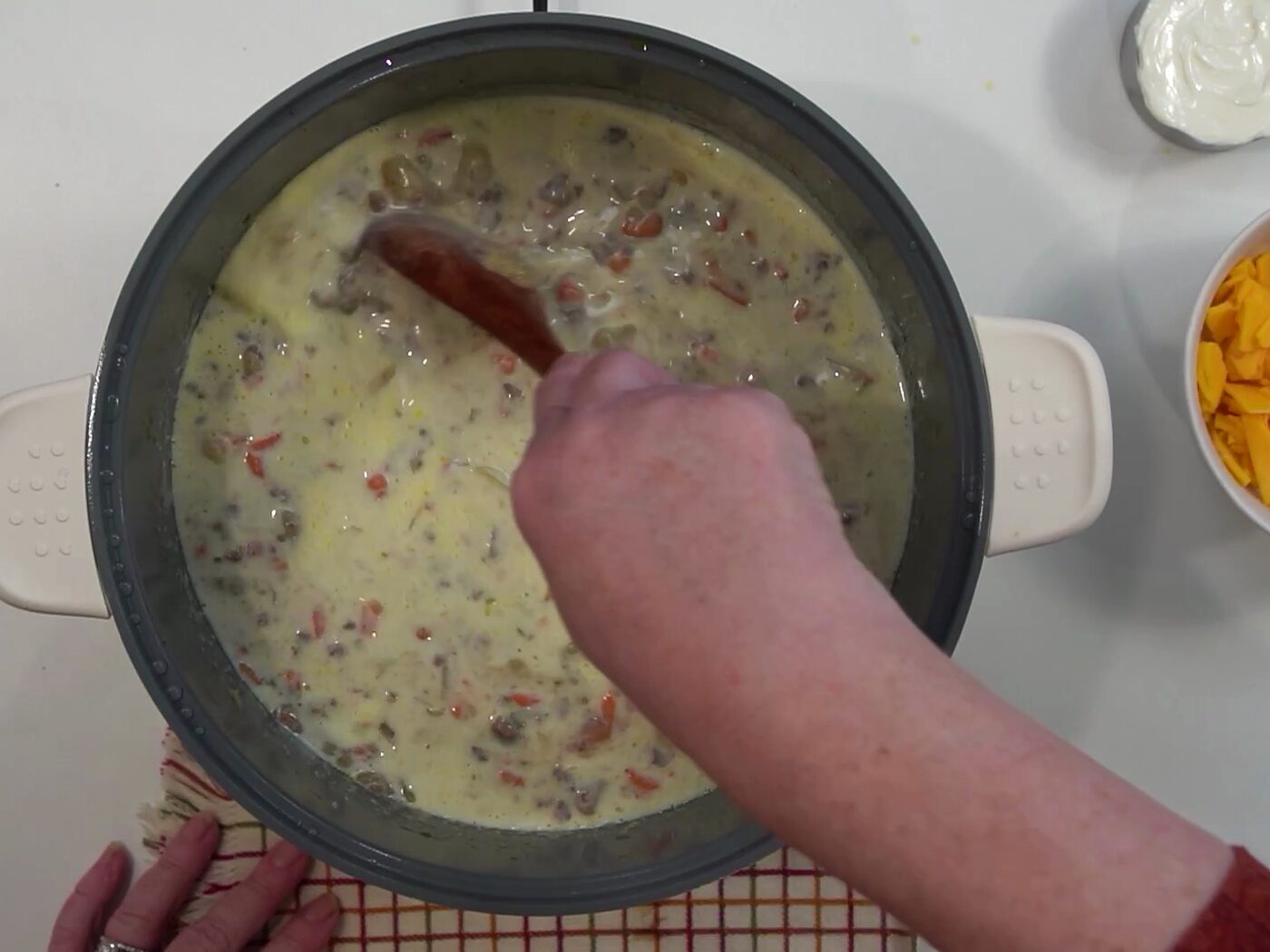 Whole milk being stirred into the potato and beef soup, turning it creamy