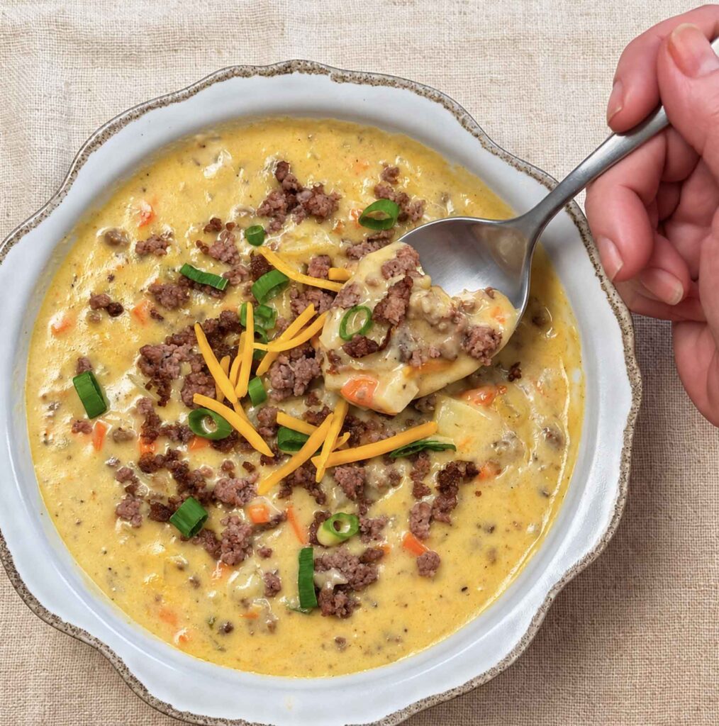 Jennifer lifting a spoonful of creamy cheeseburger soup from a bowl