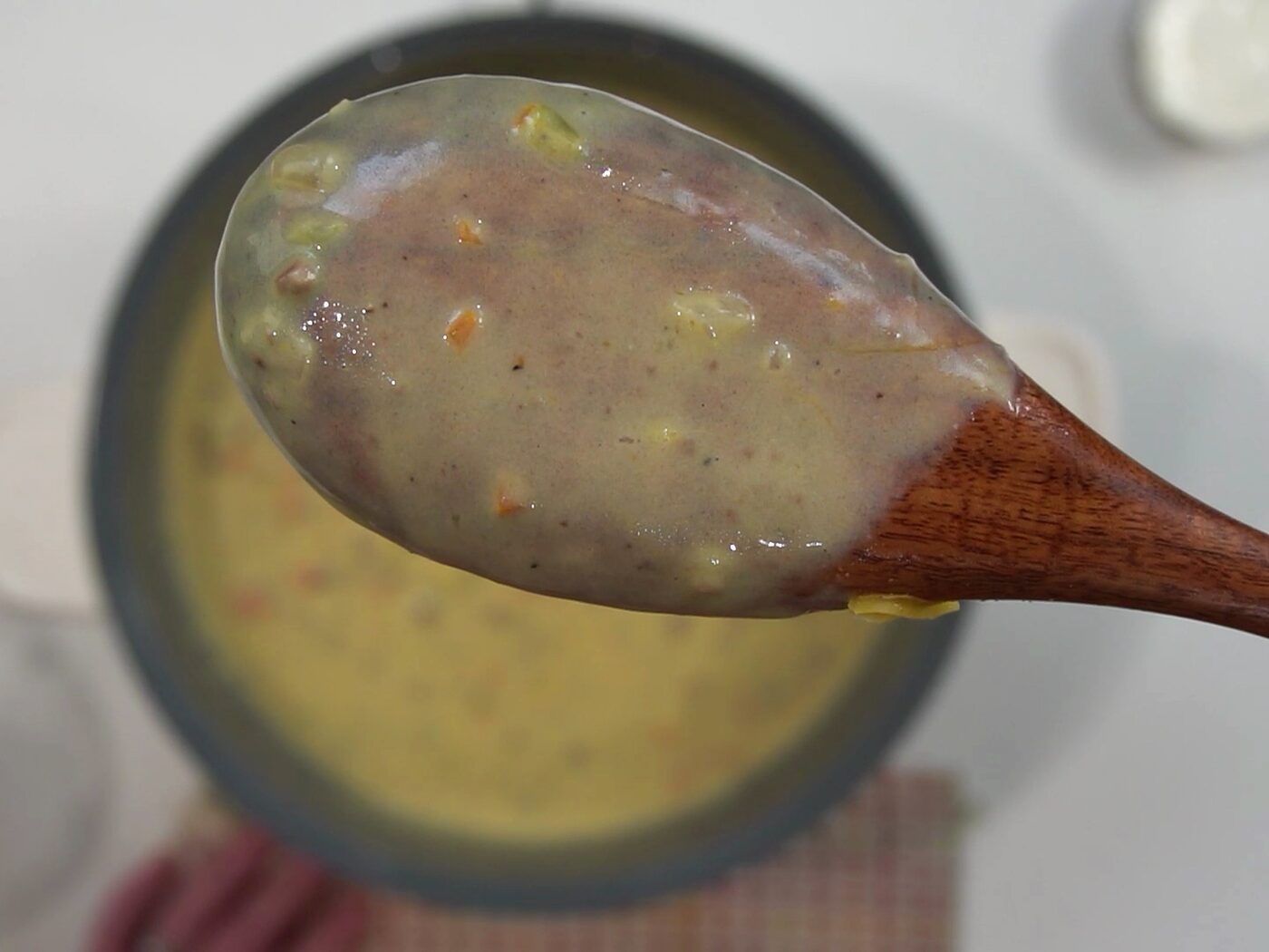 A wooden spoon coated in thick, creamy cheeseburger soup