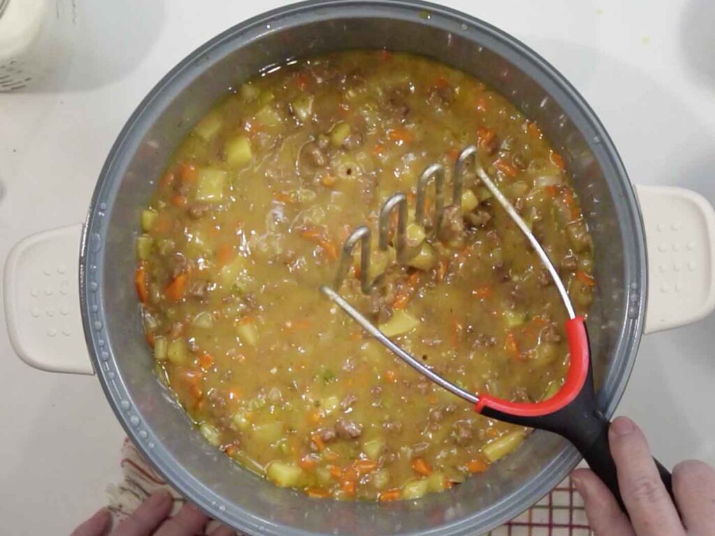 Mashing some of the potatoes in the cheeseburger soup