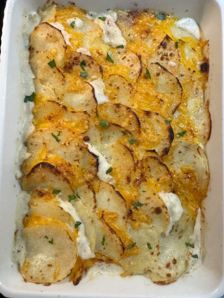 Overhead view of cheesy scalloped potatoes with golden, crispy-edged shingled slices and parsley