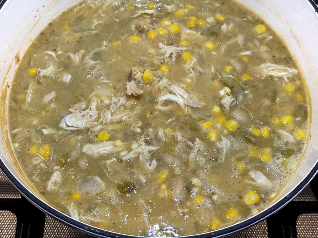 White chicken chili with chicken, corn, and beans stirred together in a Dutch oven