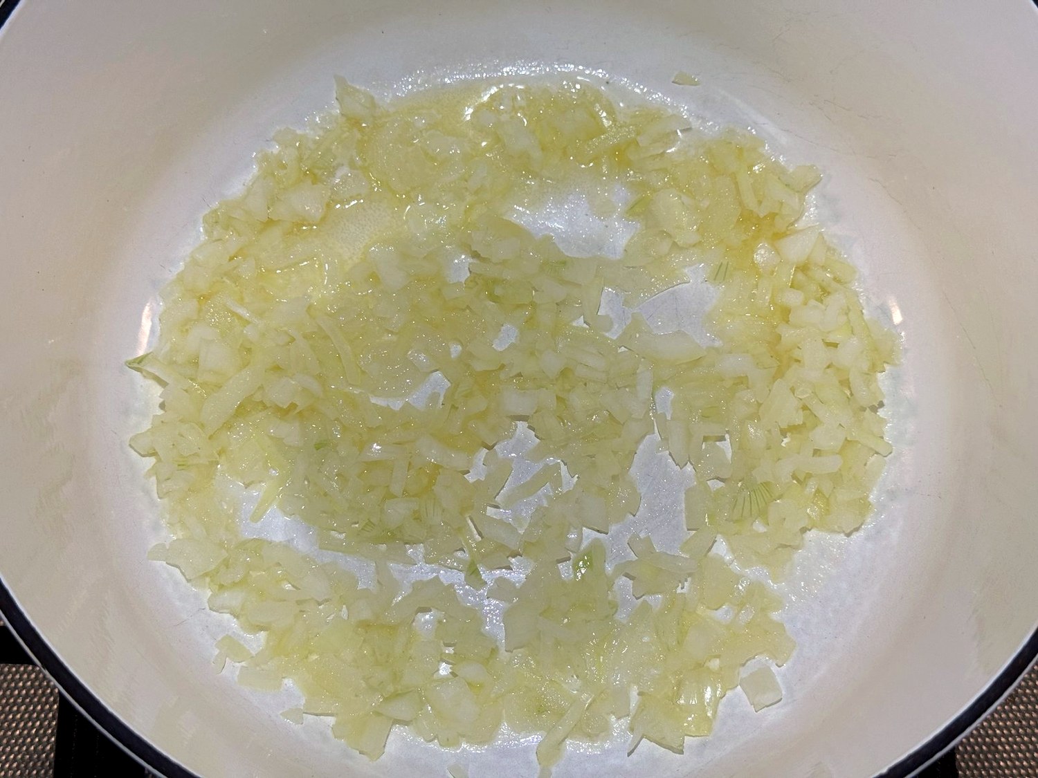 Finely chopped onion softening in butter in a white enameled Dutch oven