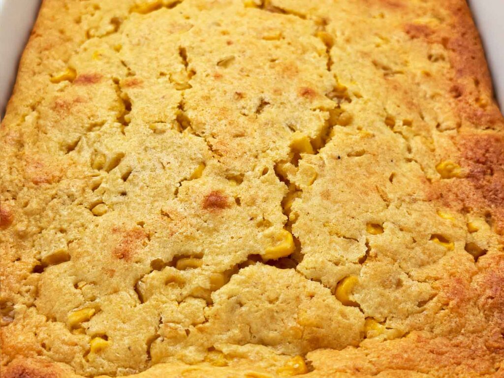 Close-up of the golden, cracked top of baked corn casserole with corn kernels showing