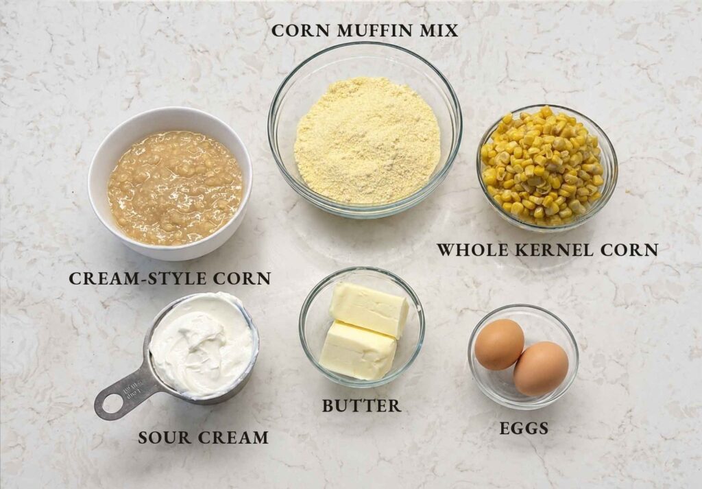 Labeled ingredients for corn casserole: cream-style corn, corn muffin mix, drained whole kernel corn, sour cream, butter, eggs