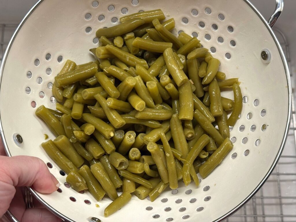Drained canned green beans in a white colander