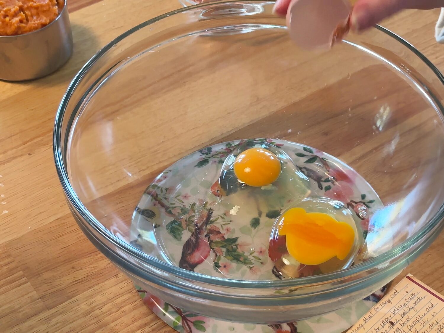 Two eggs cracked into a clear glass mixing bowl