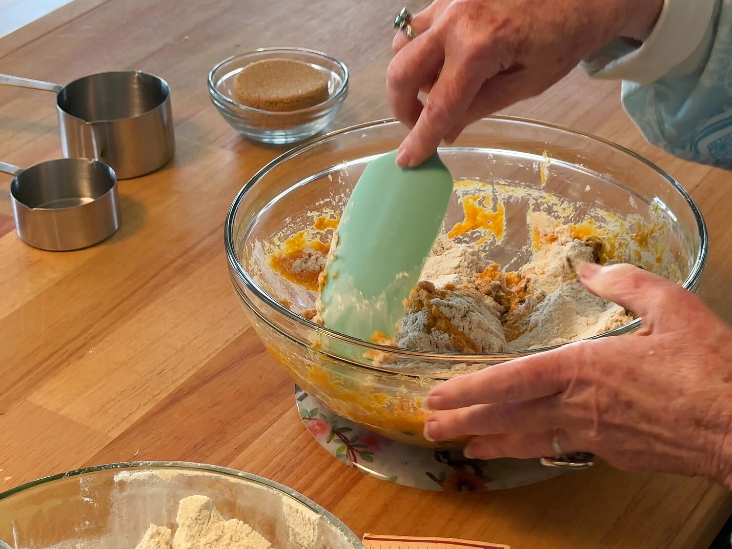 Folding flour into pumpkin muffin batter with a rubber spatula