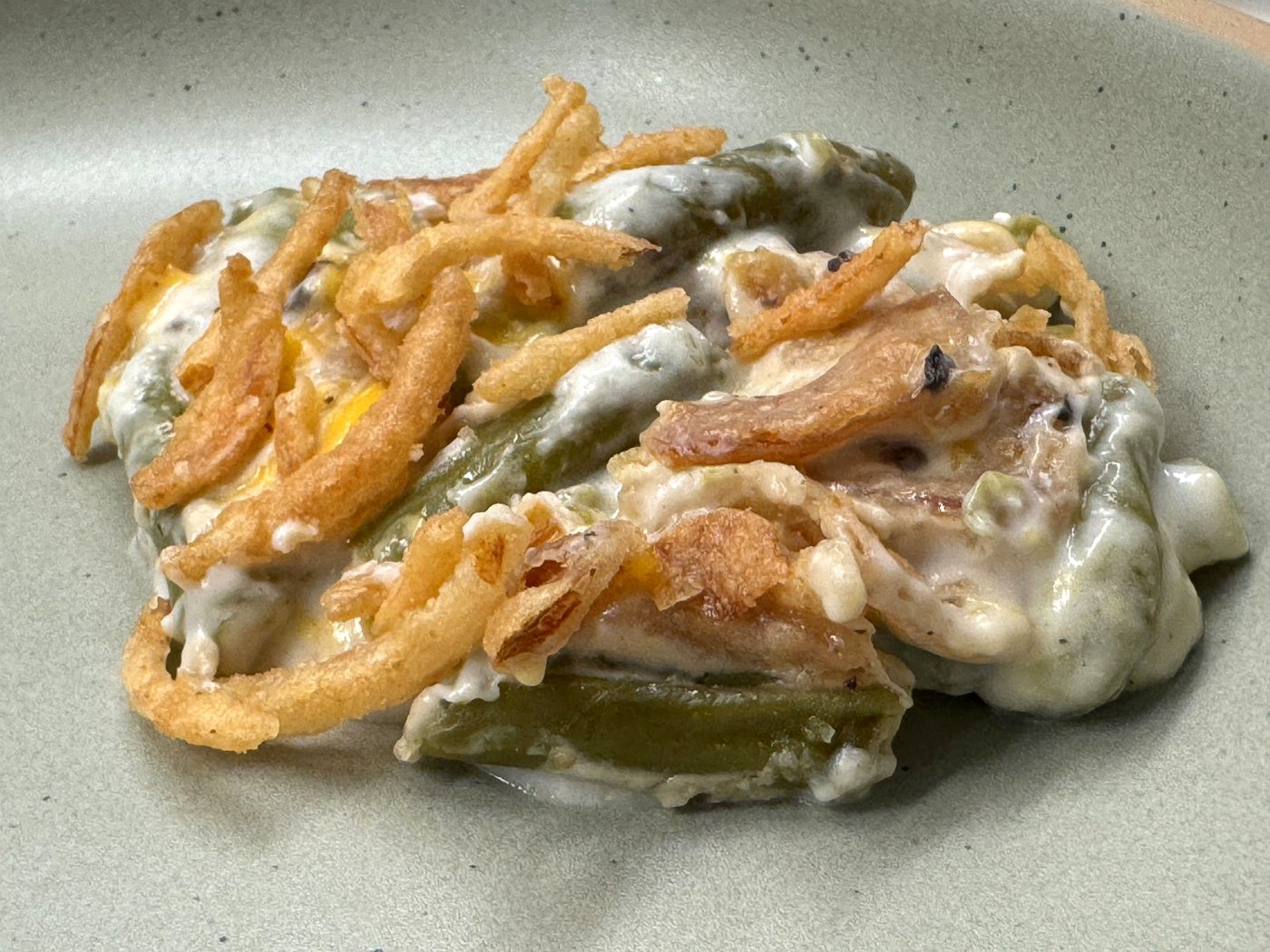 Close-up of creamy green bean casserole with crispy fried onions on a plate