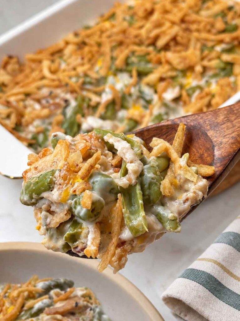 A spoonful of creamy green bean casserole being served on a plate