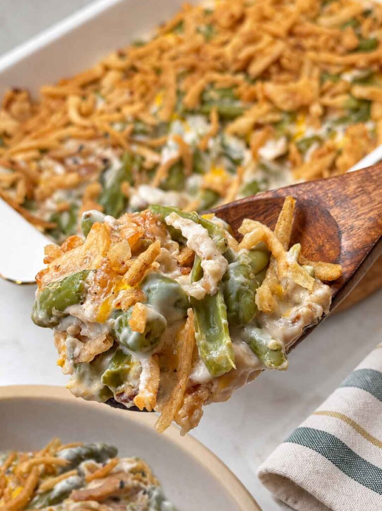 A spoonful of creamy green bean casserole being served on a plate