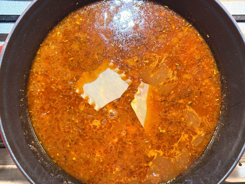 Broken lasagna noodle pieces going into the simmering soup