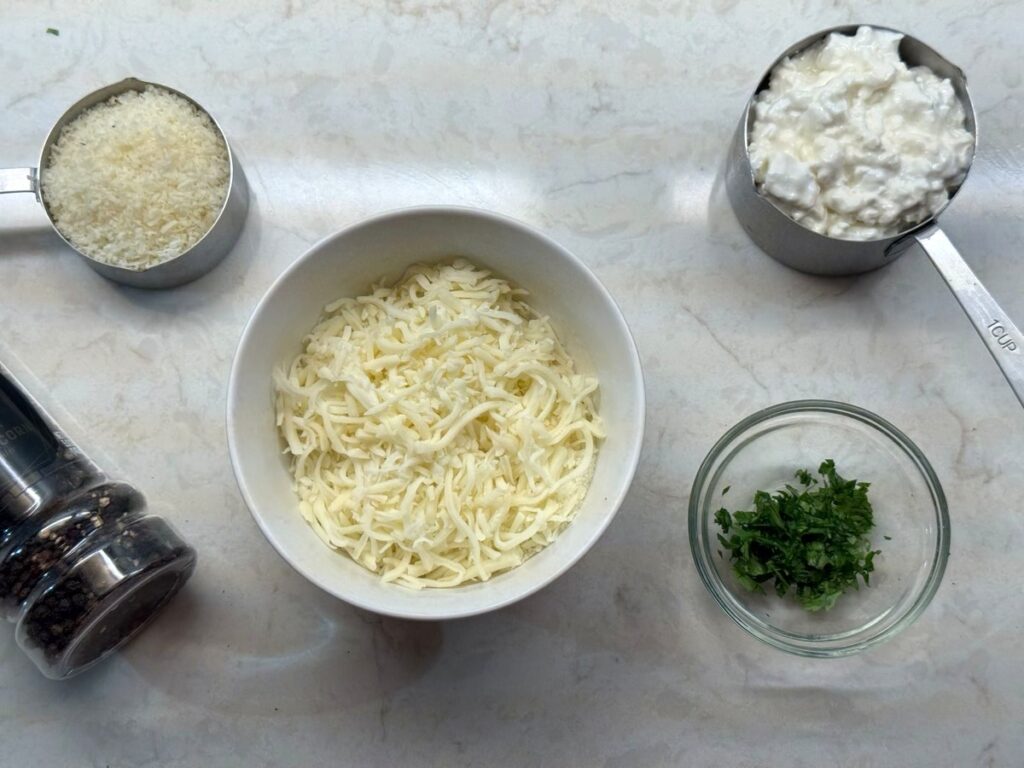 Cottage cheese, shredded mozzarella, grated parmesan, chopped parsley, and a pepper grinder for the cheese topping