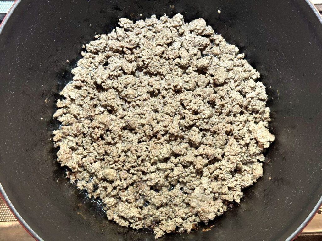 Cooked ground beef crumbles in a dark Dutch oven     