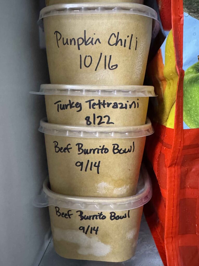 Labelled leftover containers stacked in a freezer