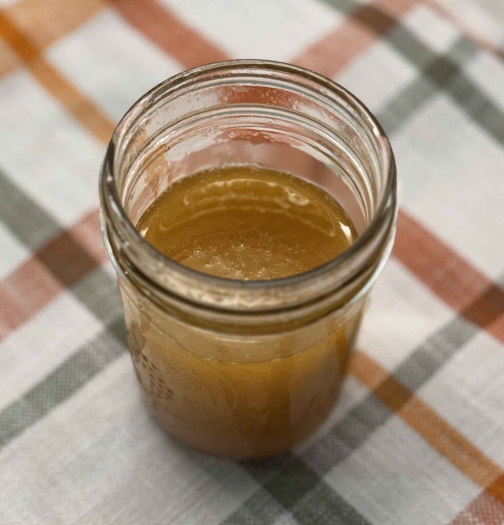 Maple vinaigrette in a small mason jar on a plaid kitchen towel