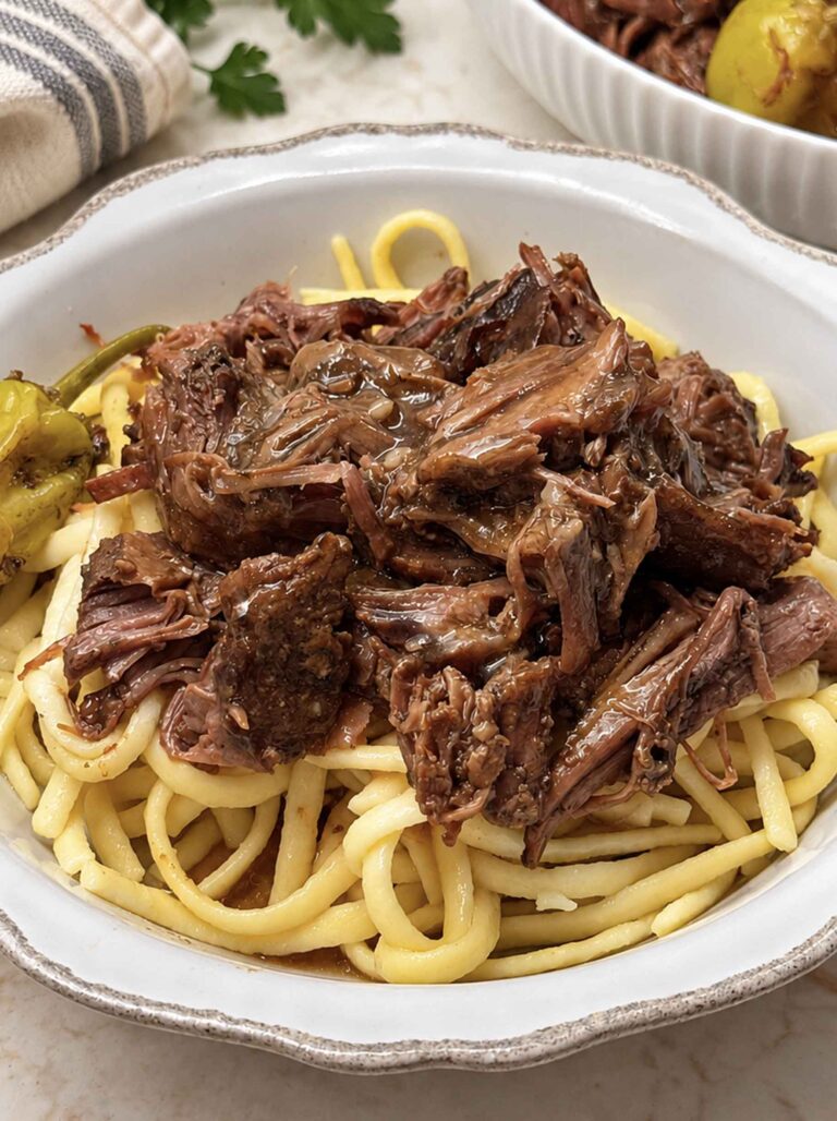 Mississippi pot roast in a white bowl over egg noodles
