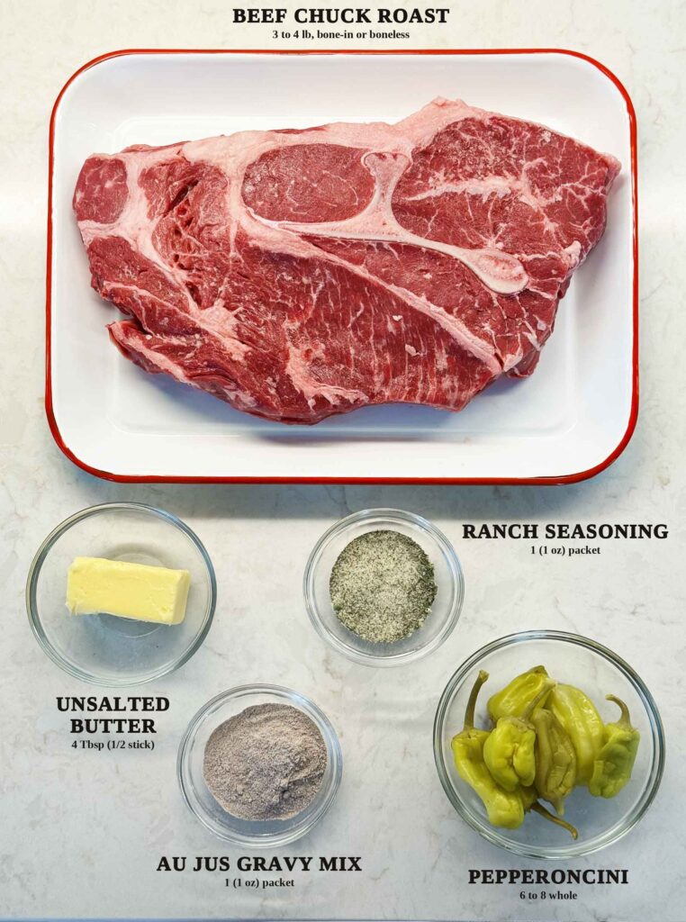 Labeled ingredients for Mississippi pot roast: a bone-in beef chuck roast, unsalted butter, ranch seasoning, au jus gravy mix, and whole pepperoncini