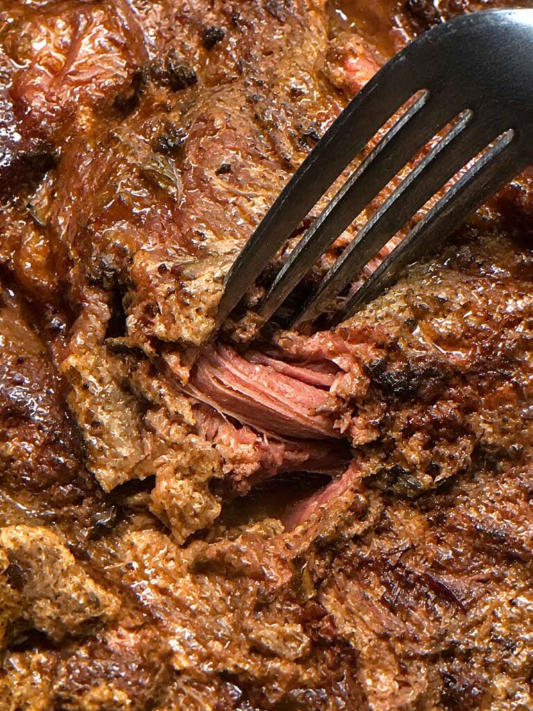 Twisting the roast with a fork to see if it is done. 