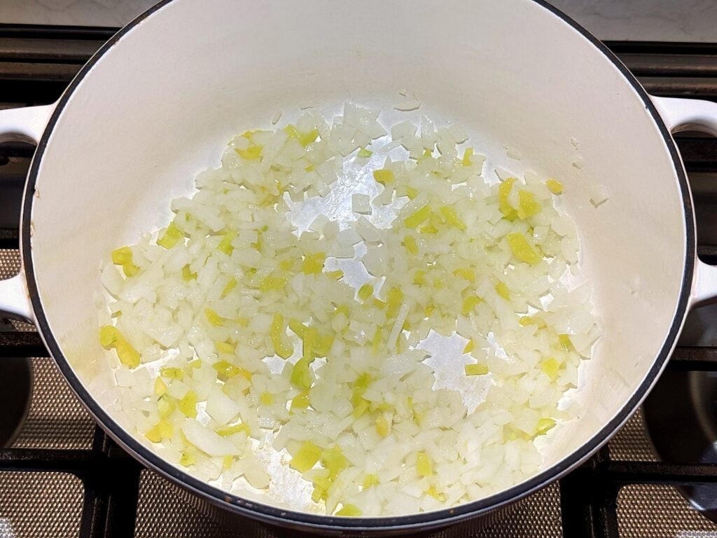 Diced onion and light-colored sweet peppers in olive oil in a white Dutch oven