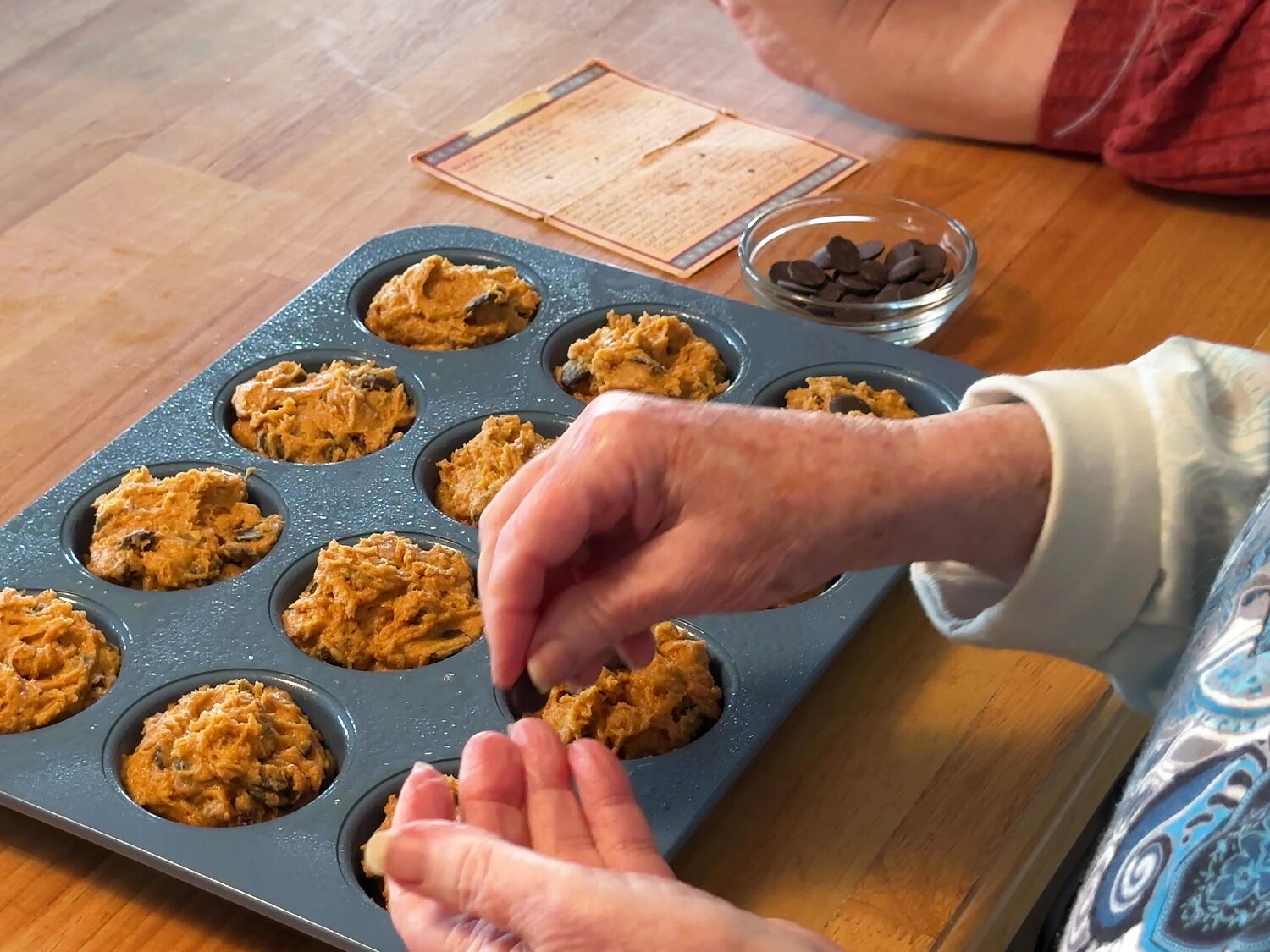 Pressing extra chocolate pieces onto the tops of unbaked pumpkin muffins
