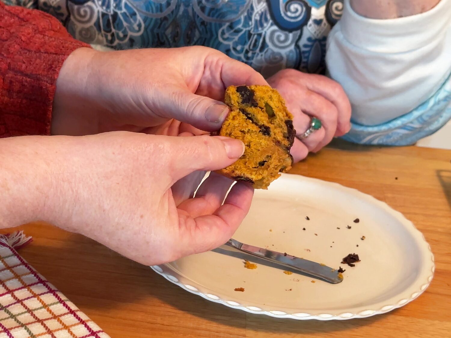 Hands breaking open a warm pumpkin chocolate chip muffin to show melted chocolate inside