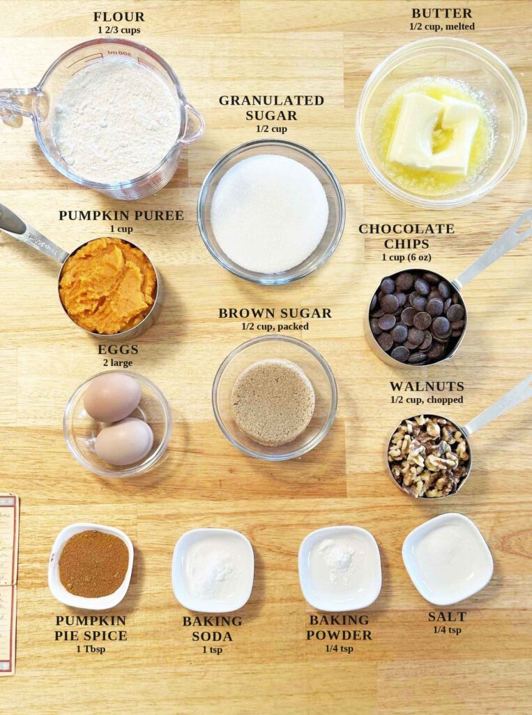Labeled ingredients for pumpkin chocolate chip muffins: flour, granulated sugar, brown sugar, butter, pumpkin puree, eggs, chocolate chips, walnuts, pumpkin pie spice, baking soda, baking powder, and salt