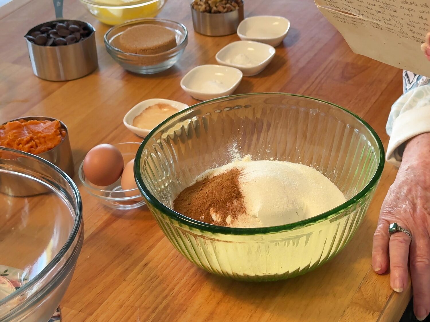 Flour, sugar, and pumpkin pie spice in a green glass mixing bowl before whisking