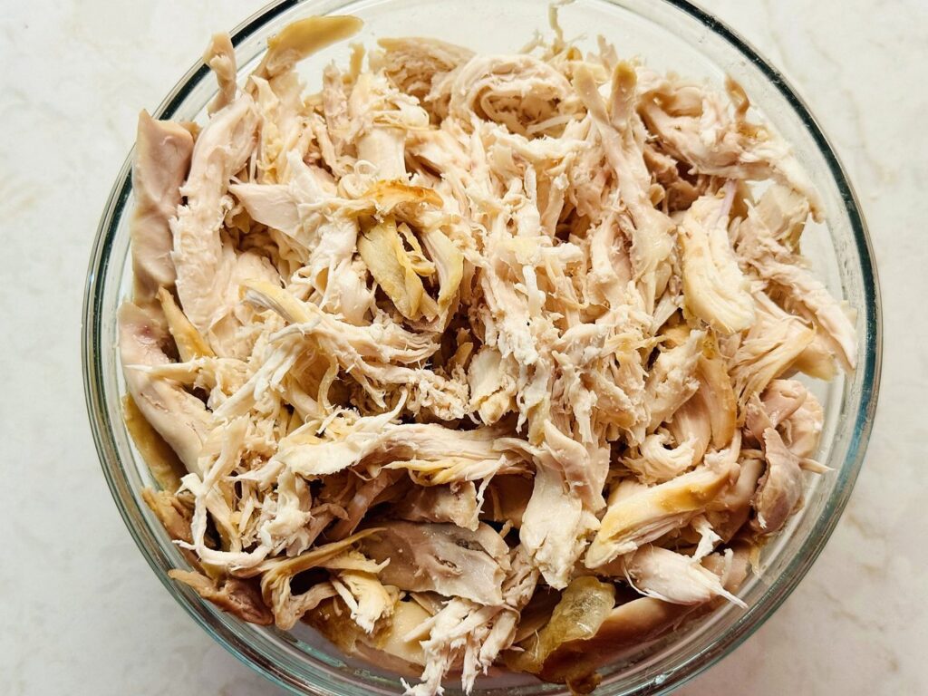 Shredded rotisserie chicken in a glass bowl