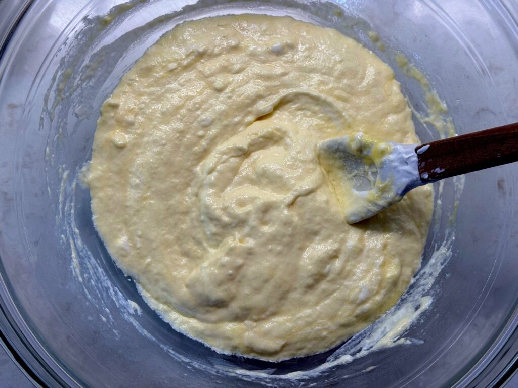 Eggs, sour cream, and melted butter whisked into a creamy mixture in a glass bowl