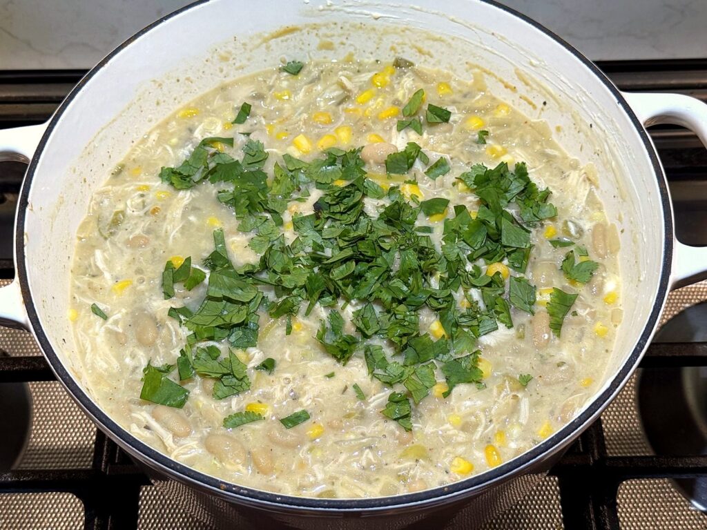 Chopped fresh cilantro on top of the creamy white chicken chili in the Dutch oven