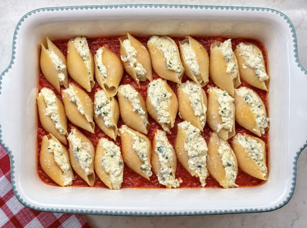 24 filled jumbo shells in three rows over marinara in a 9x13 baking dish
