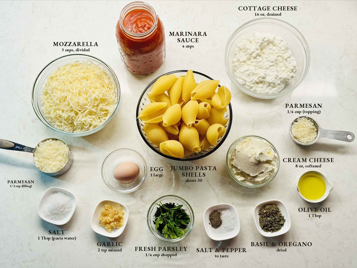 Labeled ingredients for stuffed shells: jumbo pasta shells, cottage cheese, cream cheese, mozzarella, Parmesan, marinara sauce, egg, garlic, fresh parsley, dried basil and oregano, olive oil, salt, and pepper