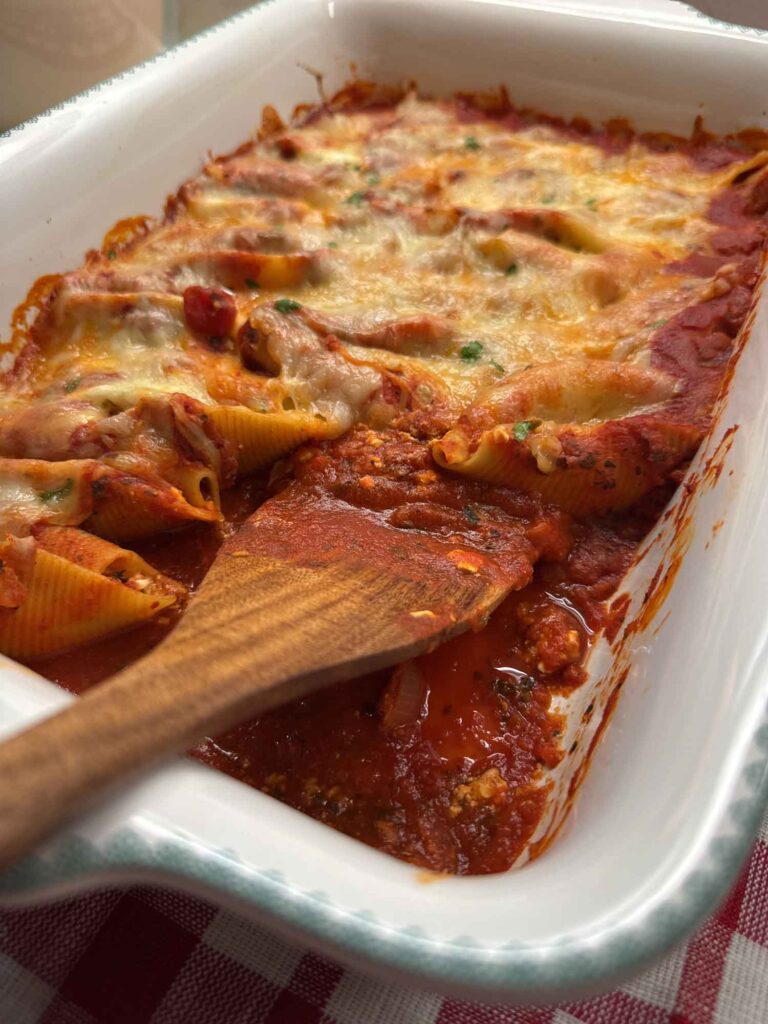 An unedited shot of a pan of stuffed shells with a spatula