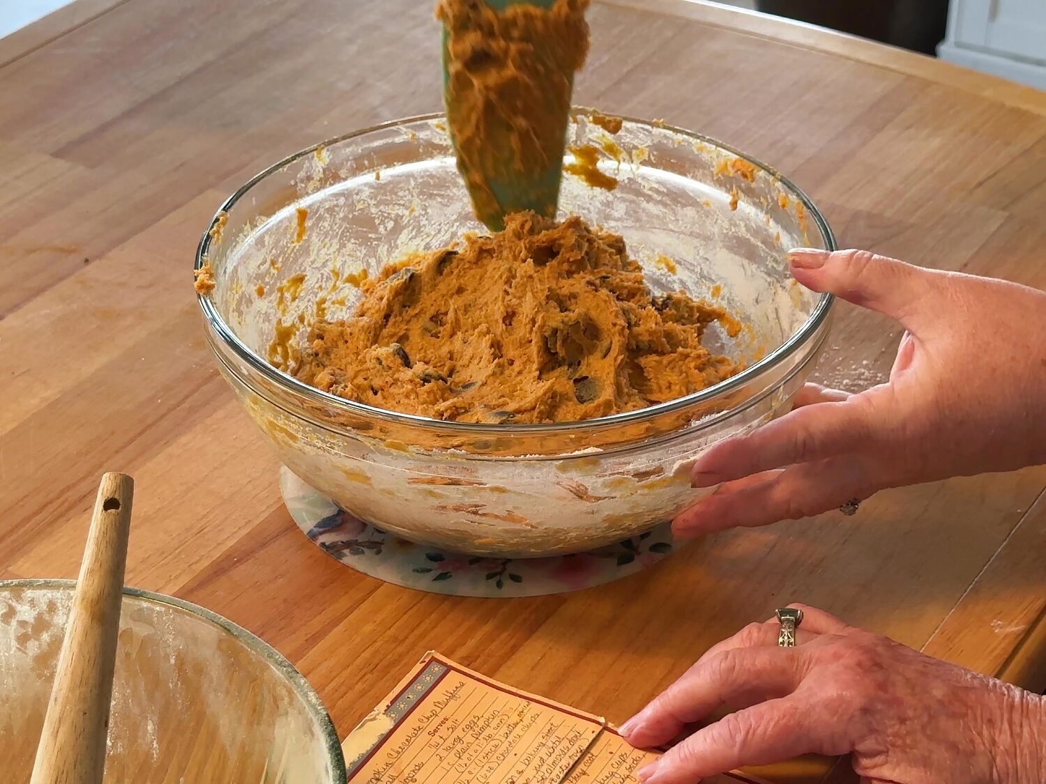 Thick pumpkin chocolate chip muffin batter on a spatula held above the bowl