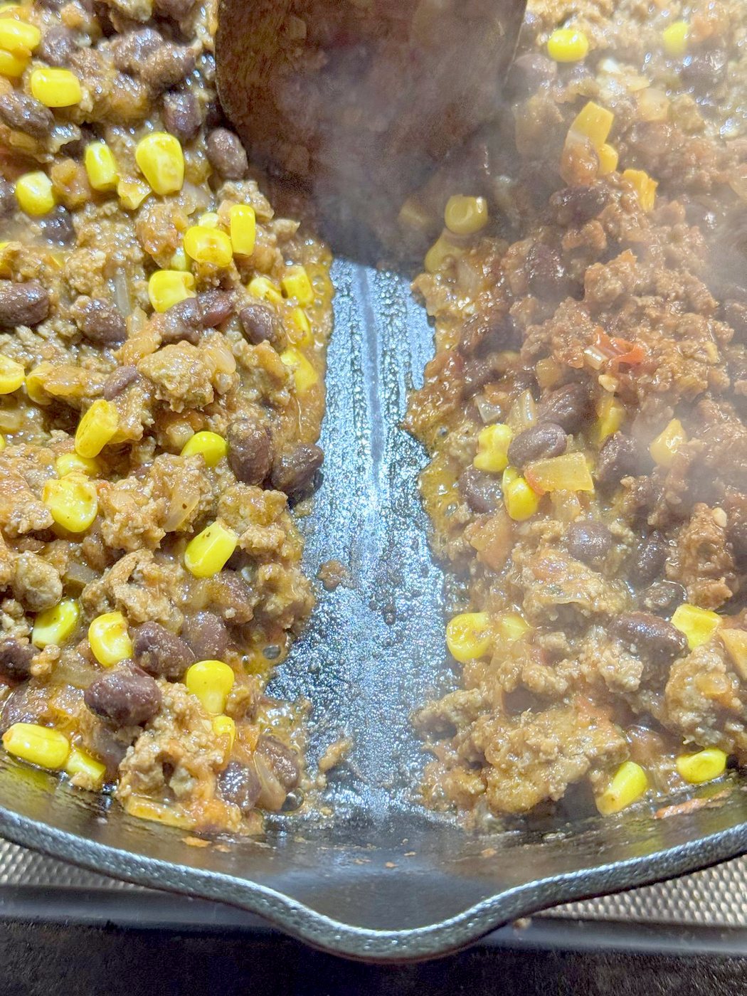 A spoon trail through thick taco casserole filling in a cast iron skillet