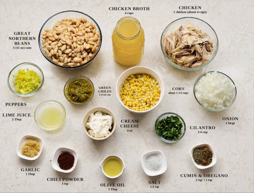 Labeled ingredients for white chicken chili: great northern beans, chicken broth, shredded chicken, sweet peppers, green chiles, corn, onion, lime juice, cilantro, cream cheese, garlic, chili powder, olive oil, salt, and cumin and oregano